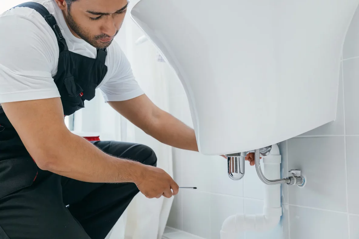 technician fixing water pipe in bathroom