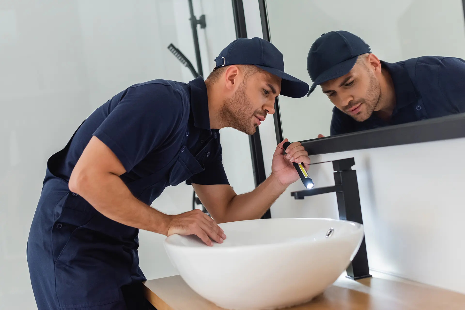 plumber with flashlight looking at sink