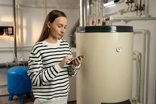 woman on phone next to boiler or water heater