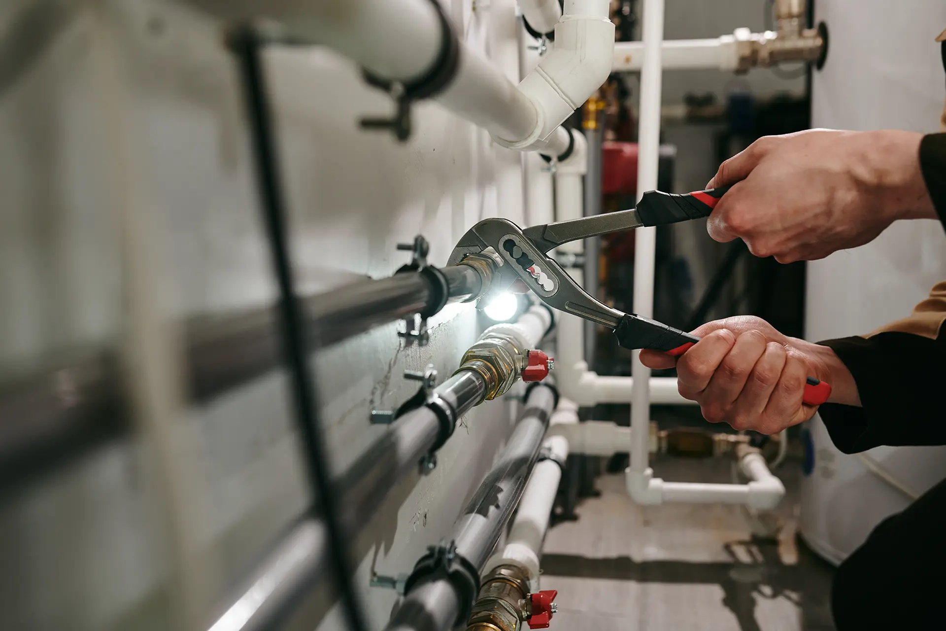 technician hands repairing pipe with wrench