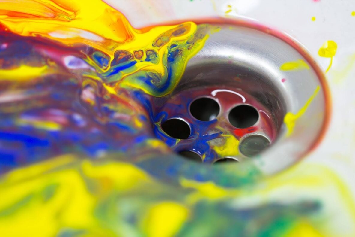 a mix of acrylic paint (blues, yellows, and greens) being rinsed down the bathroom drain